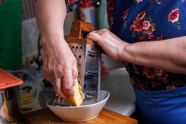 Close-up beeld van senior blanke vrouw raspt kaas