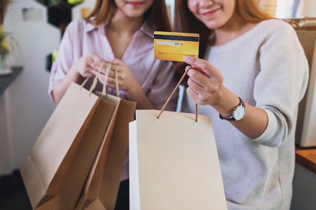 Foto close-up beeld van twee jonge vrouwen met boodschappentassen en een creditcard om te kopen