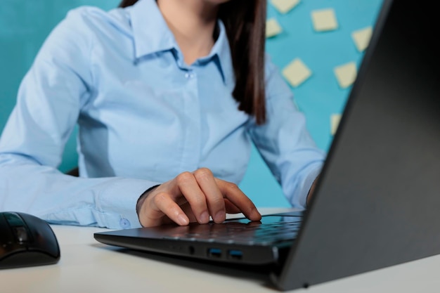 Close-up beeld van vrouw die werkt met laptop vanuit kantoor gekleed in professionele kleding. Verkoopprofessional die e-mails beantwoordt aan klanten vanaf een notebookcomputer op de werkplek.