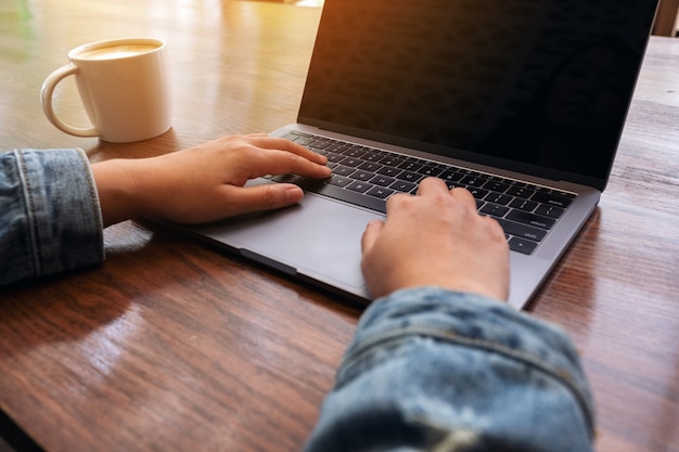 Close-up beeld van vrouw handen met behulp van en typen op laptop toetsenbord op tafel