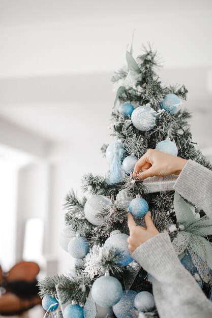 Close-up beeld van vrouw in trui kerstboom met kerstballen versieren