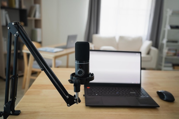Close-up beeld van werktafel werkplek met laptop en wit scherm microfoon voor streaming of gaming notebook en decoratie in de kantoorkamer thuis Werk thuis plaats in de woonkamer concept