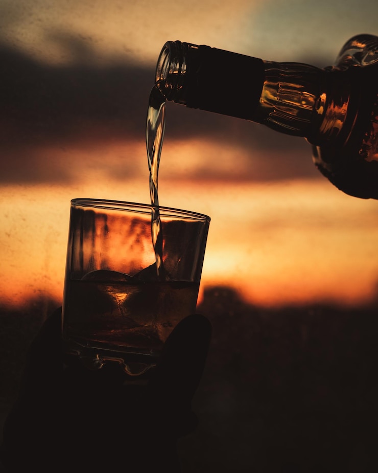 Photo close-up of beer in bottle against sunset sky