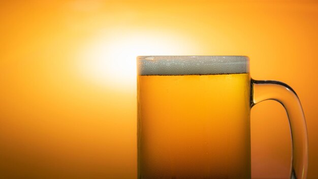 Close-up of beer glass against orange background