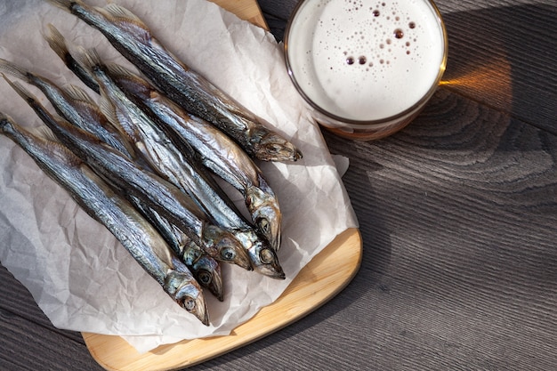 Foto avvicinamento. birra in vetro e pesce salato secco sullo sfondo di legno.