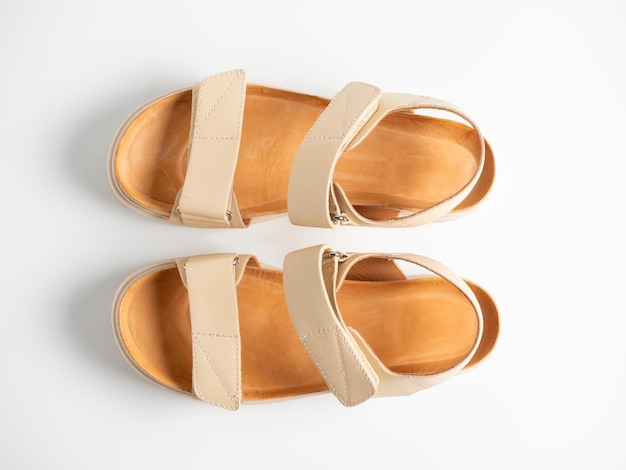 Close-up of beige leather sandals on a white background. Pair of shoes, Women's flight shoes. Top vieew flat lay