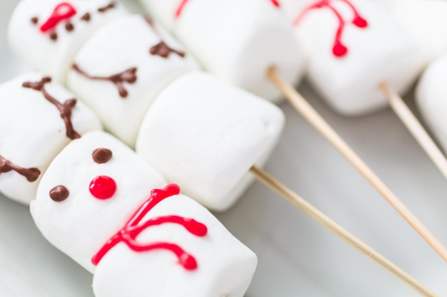 Close-up bekijken. Marshmallow-sneeuwmannen en rendieren op stokken voor warme chocolademelk.