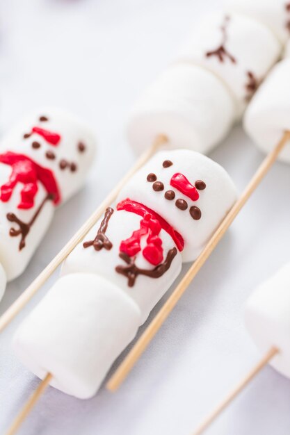 Close-up bekijken. Marshmallow-sneeuwmannen op stokken voor warme chocolademelk.