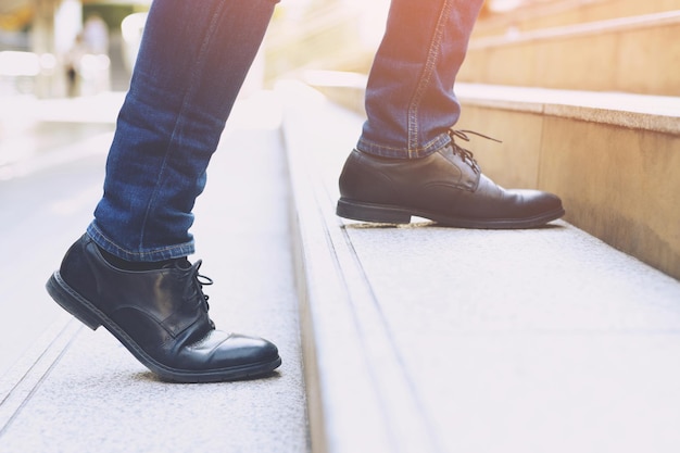 Close-up benen schoenen van jonge zakenman Een persoon lopen intensivering de trap opgaan in de moderne stad, omhoog gaan, succes, opgroeien. met filter Tonen retro vintage warm effect. trap