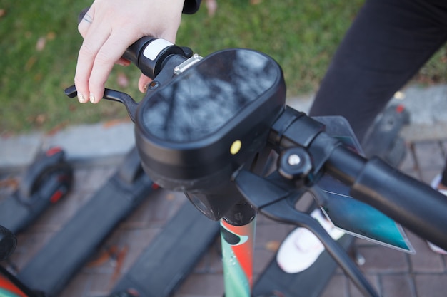 Close-up bijgesneden opname van een vrouw die in de remmen op een elektrische scooter knijpt