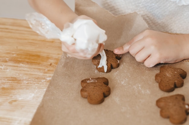 Close-up bijgesneden opname van vrouwelijke handen met suikerglazuur die peperkoekkoekjes versieren Voorbereiding op Kerstmis Nieuwjaar