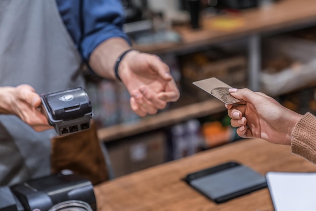 Foto close-up bijgesneden opname van vrouwelijke klant die haar creditcard doorgeeft aan coffeeshopmedewerker