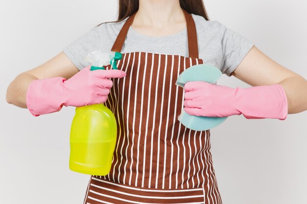 Close-up bijgesneden portret huisvrouw in roze handschoenen, gestreepte schort geïsoleerd op een witte achtergrond. Vrouw met gele spuitfles met schonere vloeistof voor het reinigen van spons. Kopieer ruimte voor advertentie.