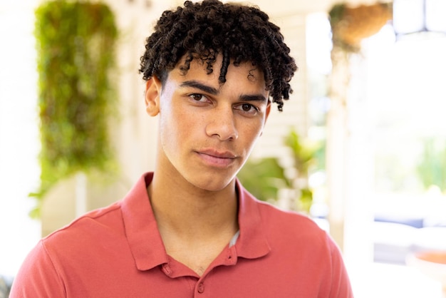 Close-up of biracial young man with dreadlocks looking at camera seriously at home, copy space. Unaltered, lifestyle, portrait, handsome and home concept.