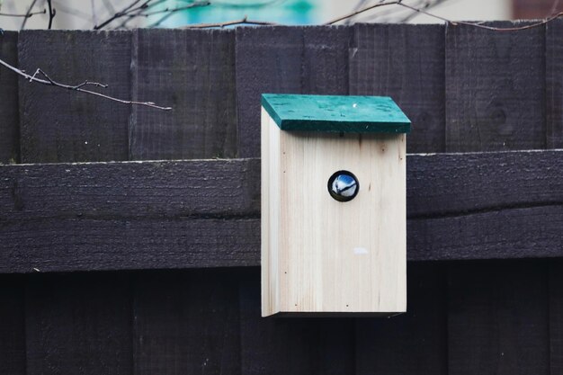 Close-up of birdhouse on wooden fence