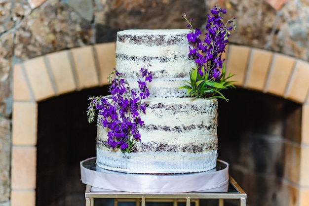 Foto primo piano della torta di compleanno decorata con fiori di lavanda nella sala banchetti davanti al caminetto