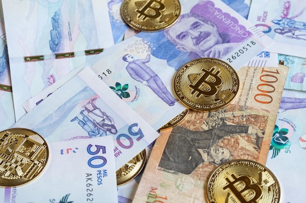 Photo close up of bitcoins over colombian banknotes