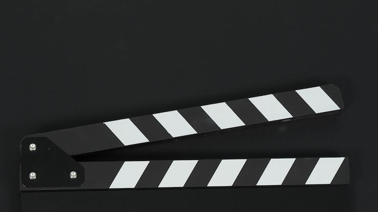 Photo close up of black clapper board or movie slate on black blackground.