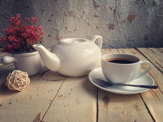 Close-up of black coffee by teapot and flower vase on table