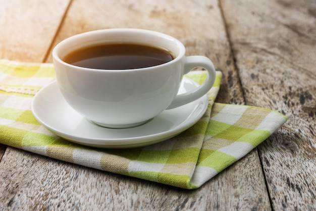 Photo close-up of black coffee on napkin at wooden table