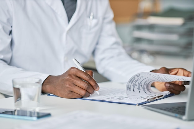 Photo close up black doctor filling papers at desk in office working in clinic