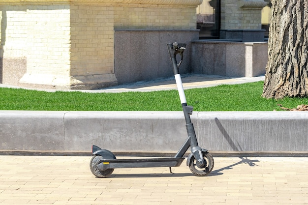 Close up of black electric kick scooter at cityscape.