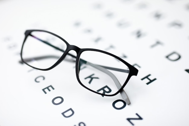 Close-up of black glasses laying on paper with letters. Thing for better vision. Check sight. Simple stylish eyewear. Ophthalmology clinic and modern medicine concept