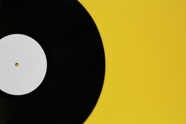 Foto primo piano di vecchi dischi in vinile nero per riprodurre dischi vintage su sfondo giallo con spazio per la copia del testo
