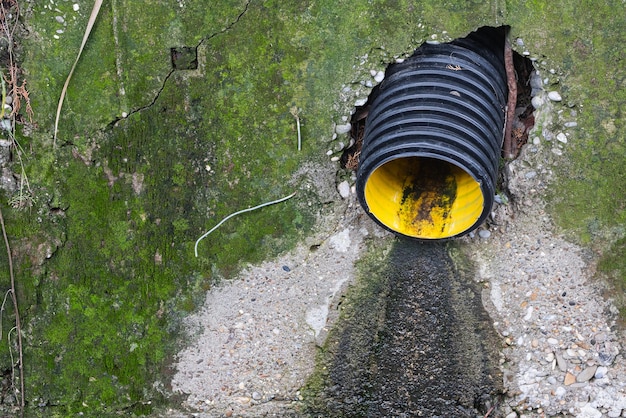 Close-up black pipe with sewage dirty water flows into the city
drain