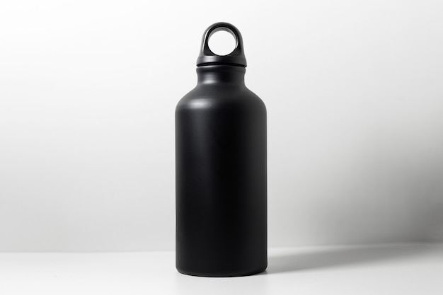 Close-up of black reusable aluminum eco thermo bottle for water on wall of white.