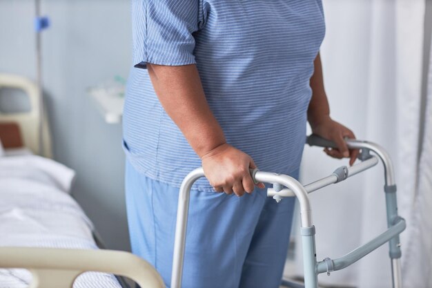 Close up of black senior woman leaning on walker support in hospital room