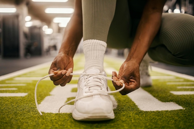 Photo close up of a black sportswoman39s hands tying shoelace on shoelace on sneaker at gym