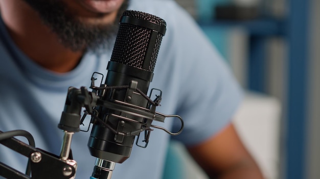 Close up of black vlogger using microphone on podcast. Social media influencer talking to subscribers on camera for vlog. African american blogger working with modern equipment and gear.