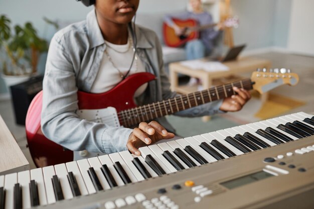 집에서 음악을 작곡하는 동안 피아노 건반을 누르는 흑인 젊은 여성의 클로즈업