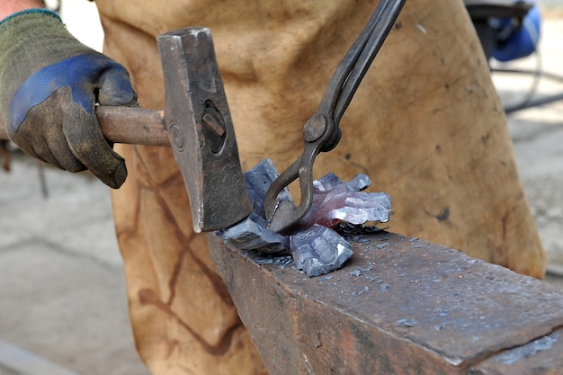 Close up of a blacksmith forge an iron product with a hammer and tongs Handmade concept