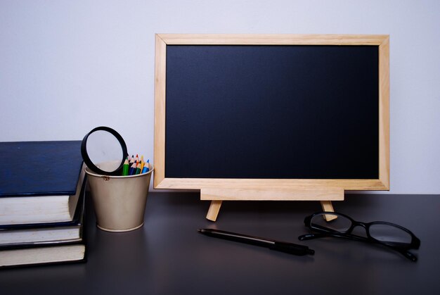 Photo close-up of blank blackboard with school supplies on table