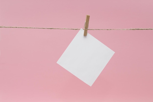 close-up of blank notes hanging on rope against pink background