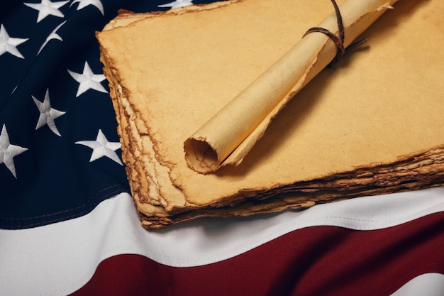 Close up blank old vintage yellow paper sheets and scroll on
cotton embroidered us national flag background, symbol of american
history, elevated high angle view