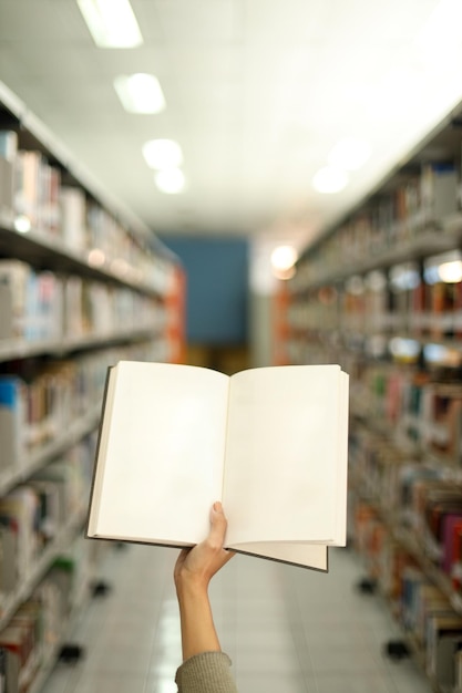 Close up blank pages of book for text or ads with library bookshelves on the background