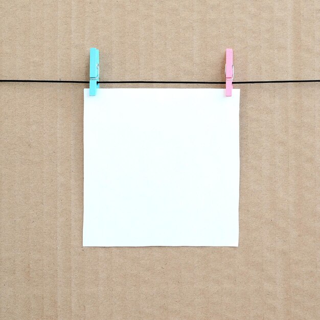 Photo close-up of blank paper hanging against cardboard