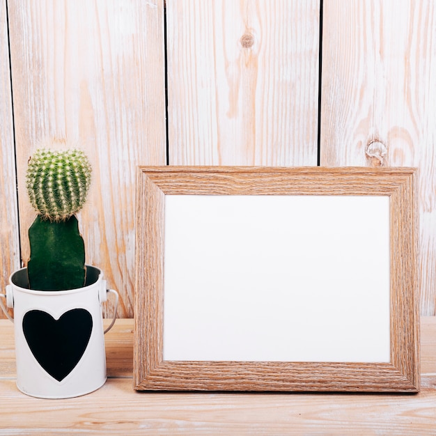 Close-up of blank photo frame and succulent plant with heartshape on pot