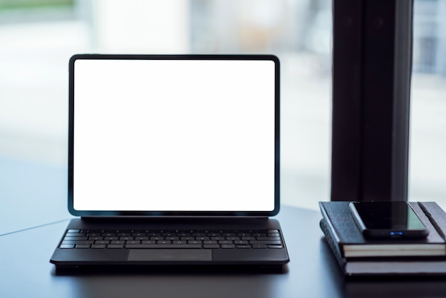 Close up of blank screen digital tablet with office supplies on black wooden table.