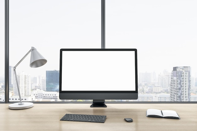 Close up of blank white computer monitor on wooden office
desktop with objects lamp and supplies on panoramic window and city
view background mock up 3d rendering