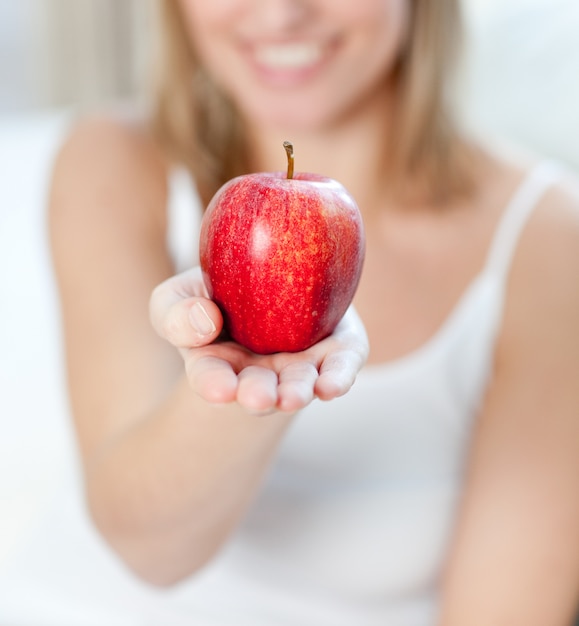 Close-up of a blond woman showing an apple