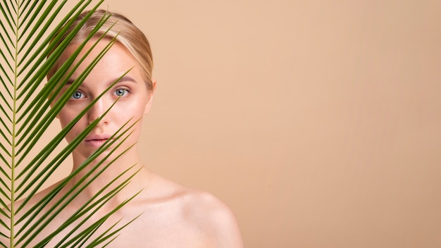 Photo close-up blonde model behind a plant with copy-space