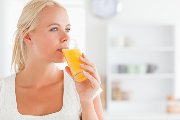 Foto chiuda in su di una donna bionda che beve il succo