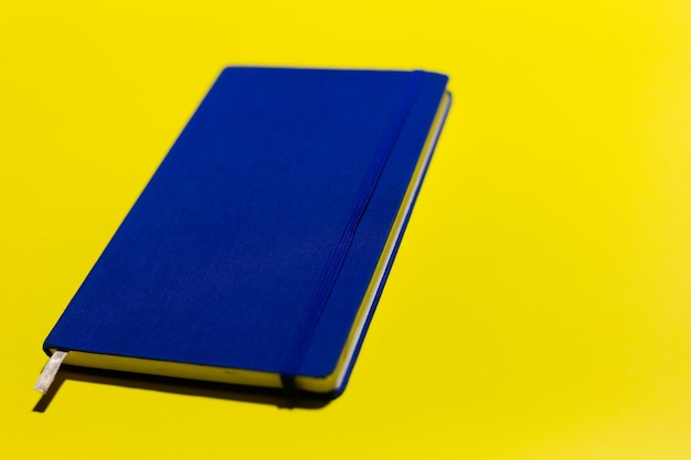 Close-up of blue notebook on yellow wall.