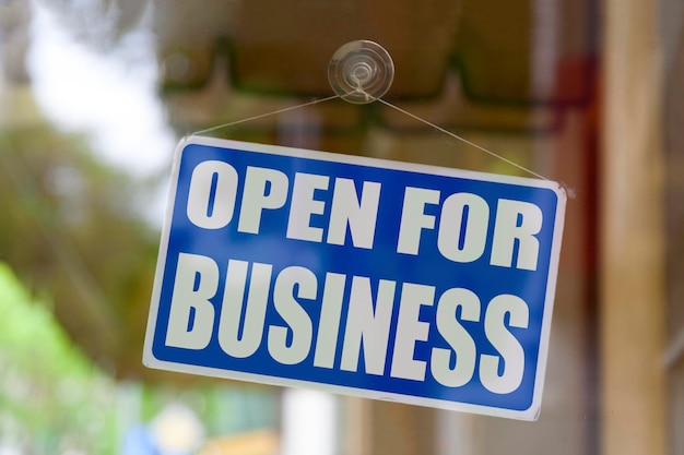 Photo close-up on a blue open sign in the window of a shop displaying the message open for business