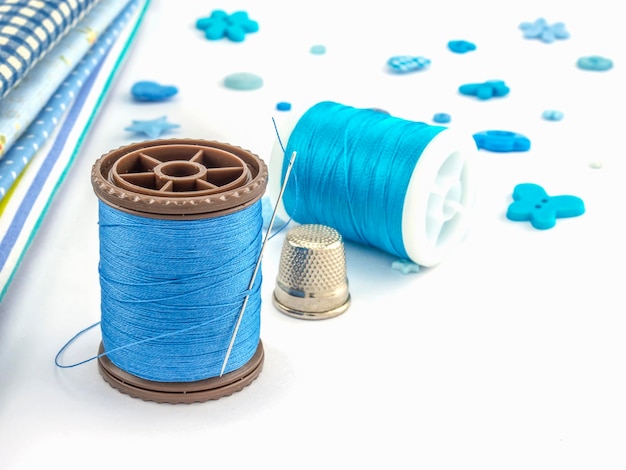 Photo close up of blue thread with needle on white background