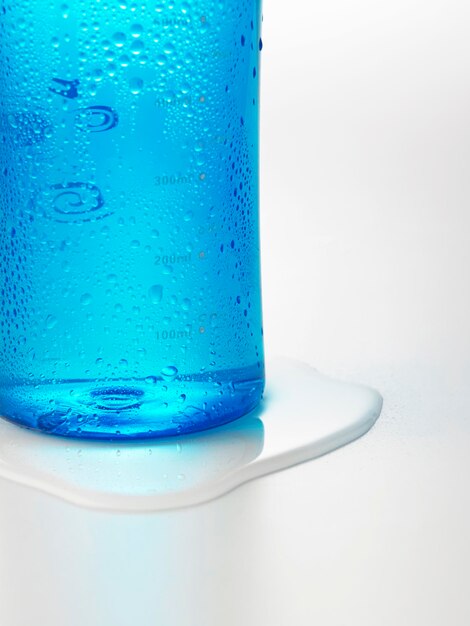 Foto close-up di una bottiglia d'acqua blu su sfondo bianco